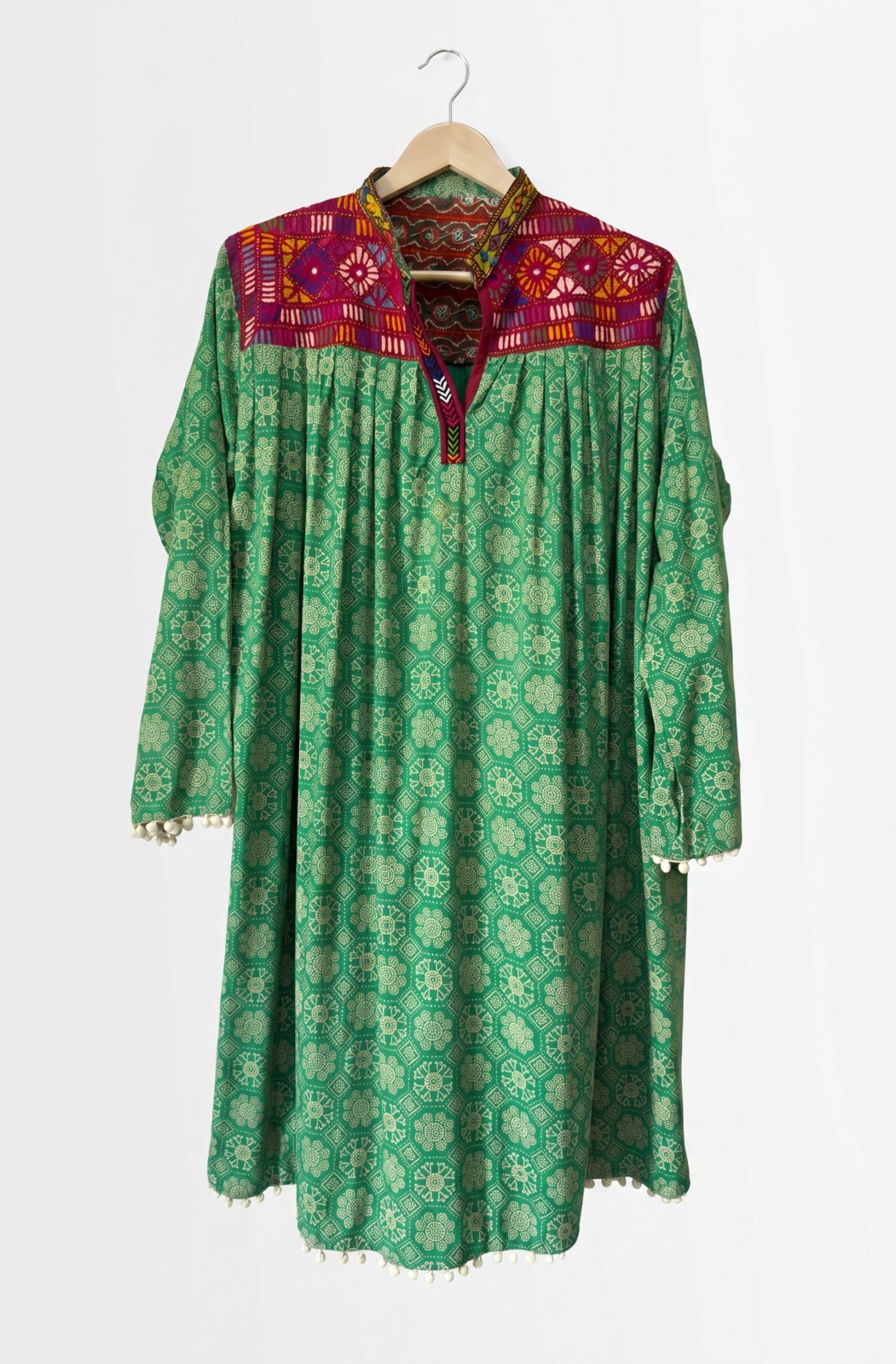 Hand-embroidered green kurta with a multicolour mirror-work yoke and pom-pom trim, handmade by women artisans in Tharparkar, Sindh