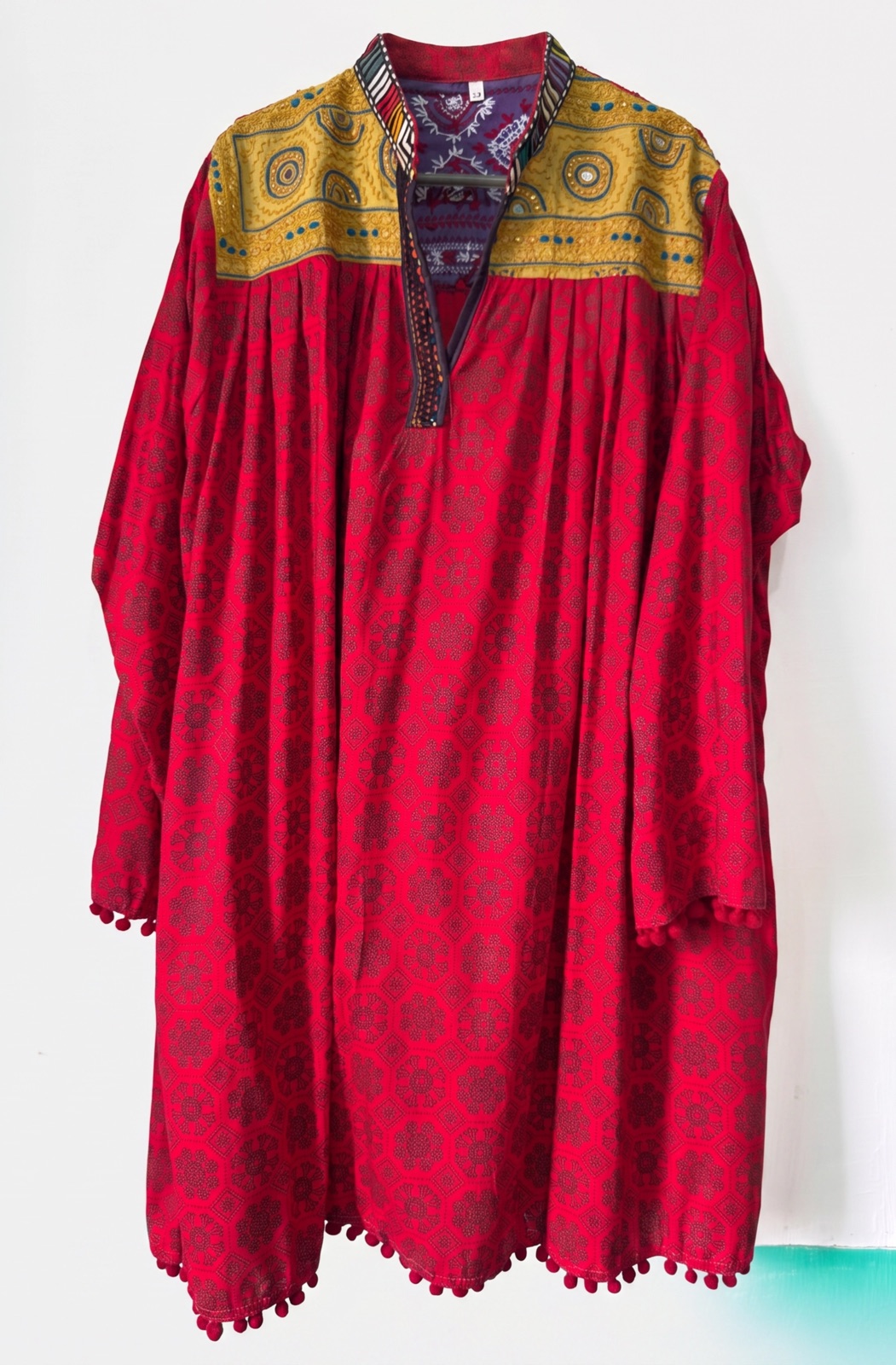 Hand-embroidered red frock-style kurta with a mustard mirror-work yoke, handmade in Tharparkar, Sindh