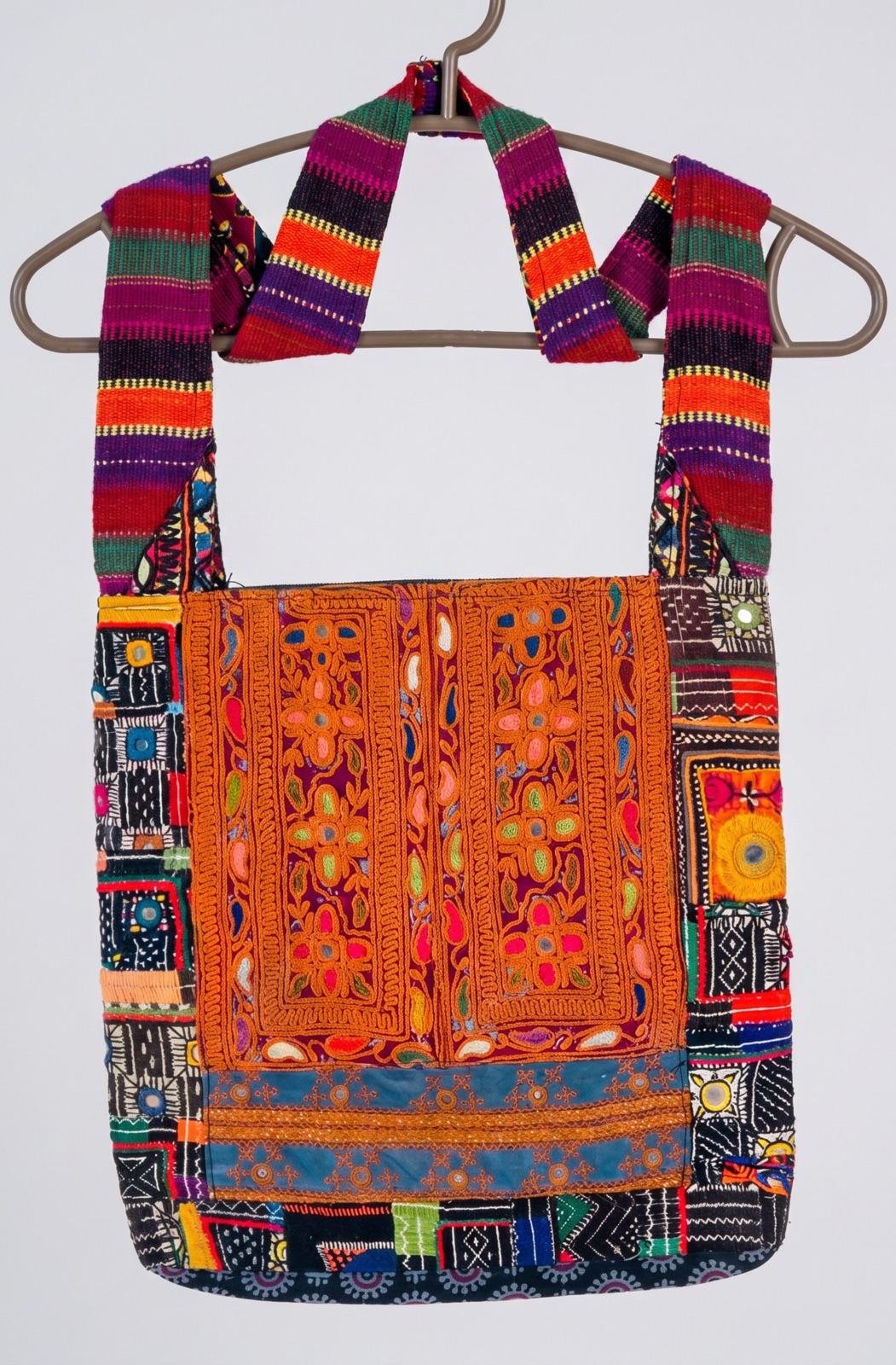 Orange and black embroidered shoulder bag with a woven striped strap and mirror-work detail, handmade in Tharparkar, Sindh